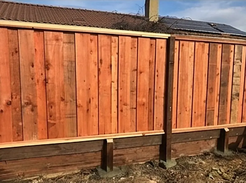 A cedar fence built over a retaining wall