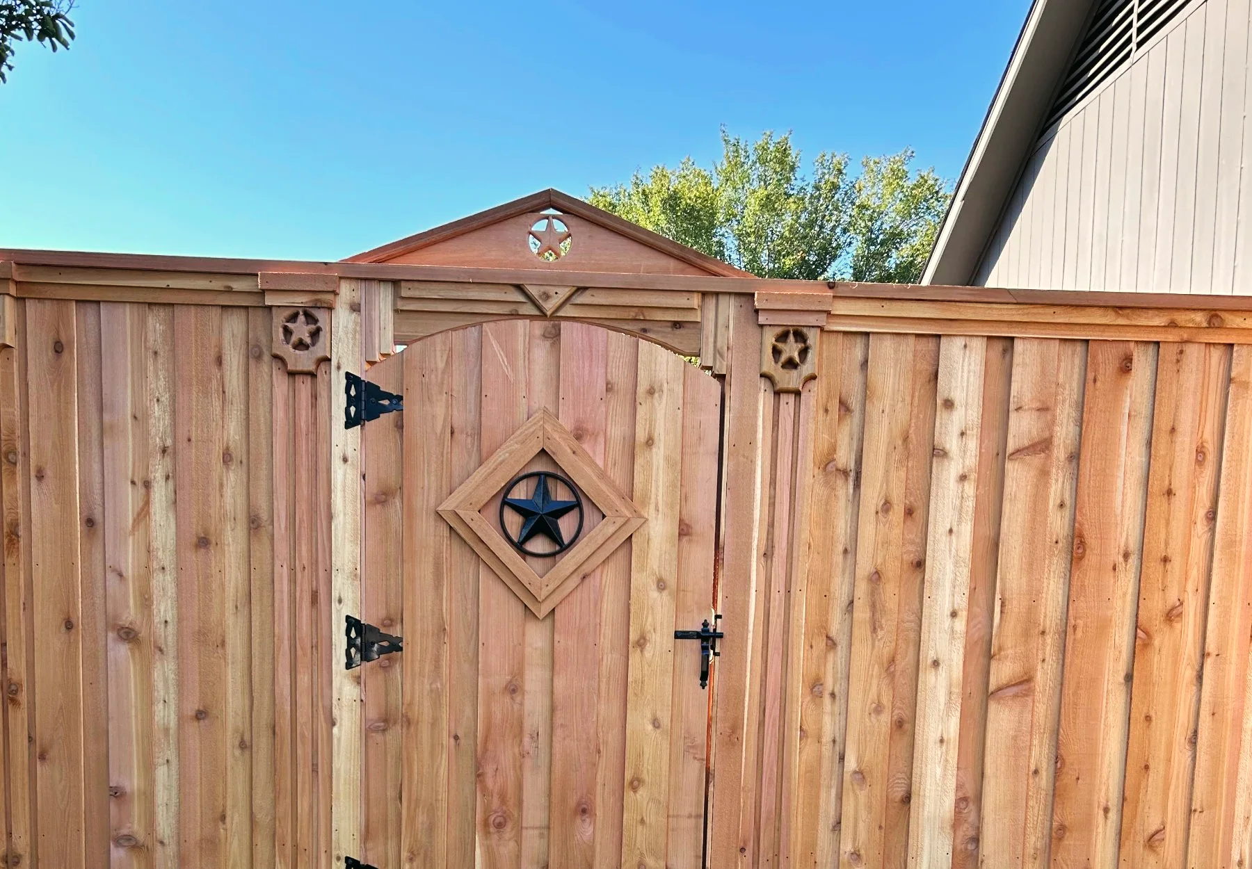 Cedar fence gate with a Texas star and a peaked top, built by Grass DFW